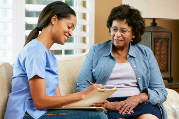 African-American nurse taking notes during visit with African-American patient